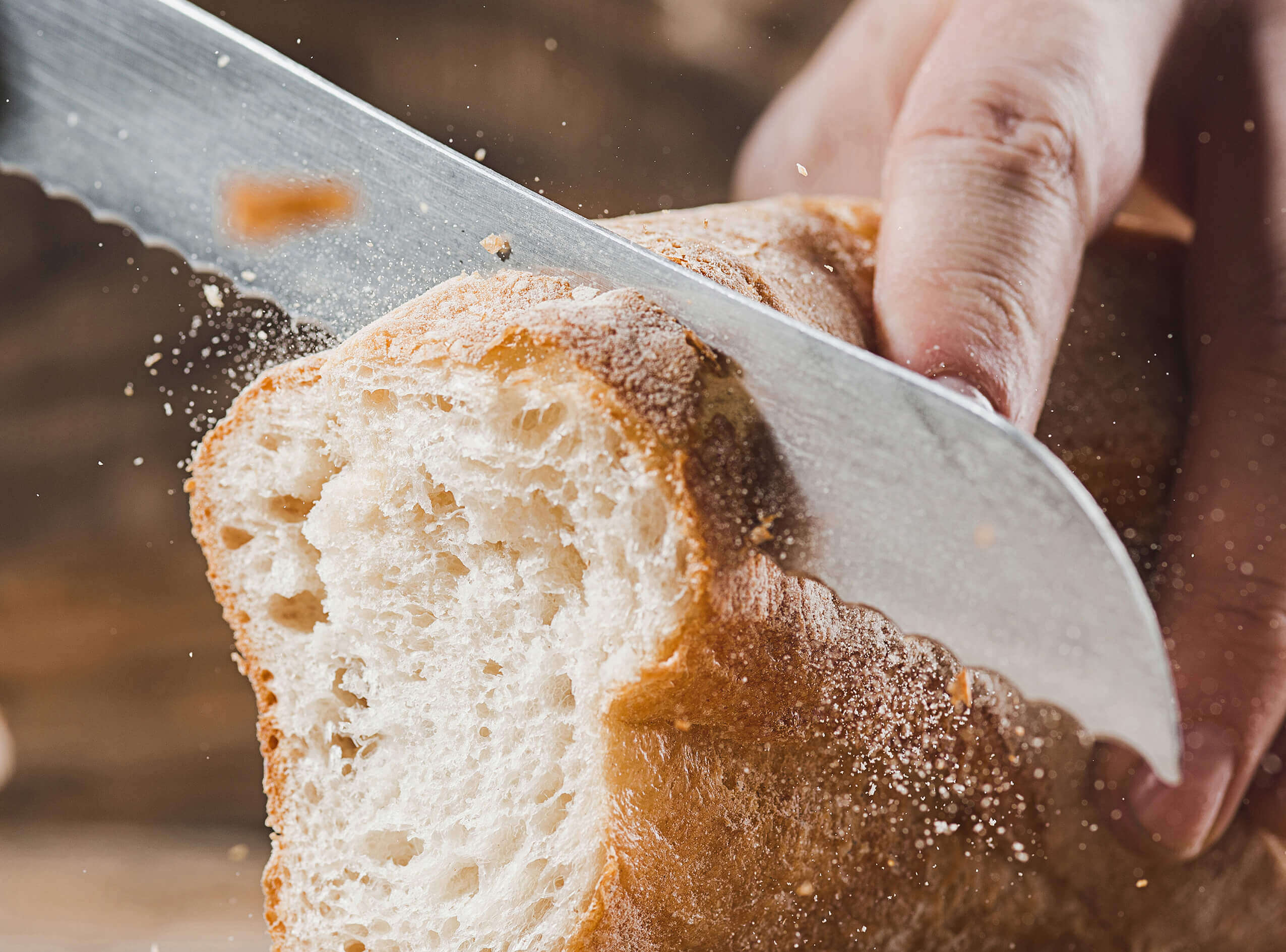 Professional knife slicing loaf of bread